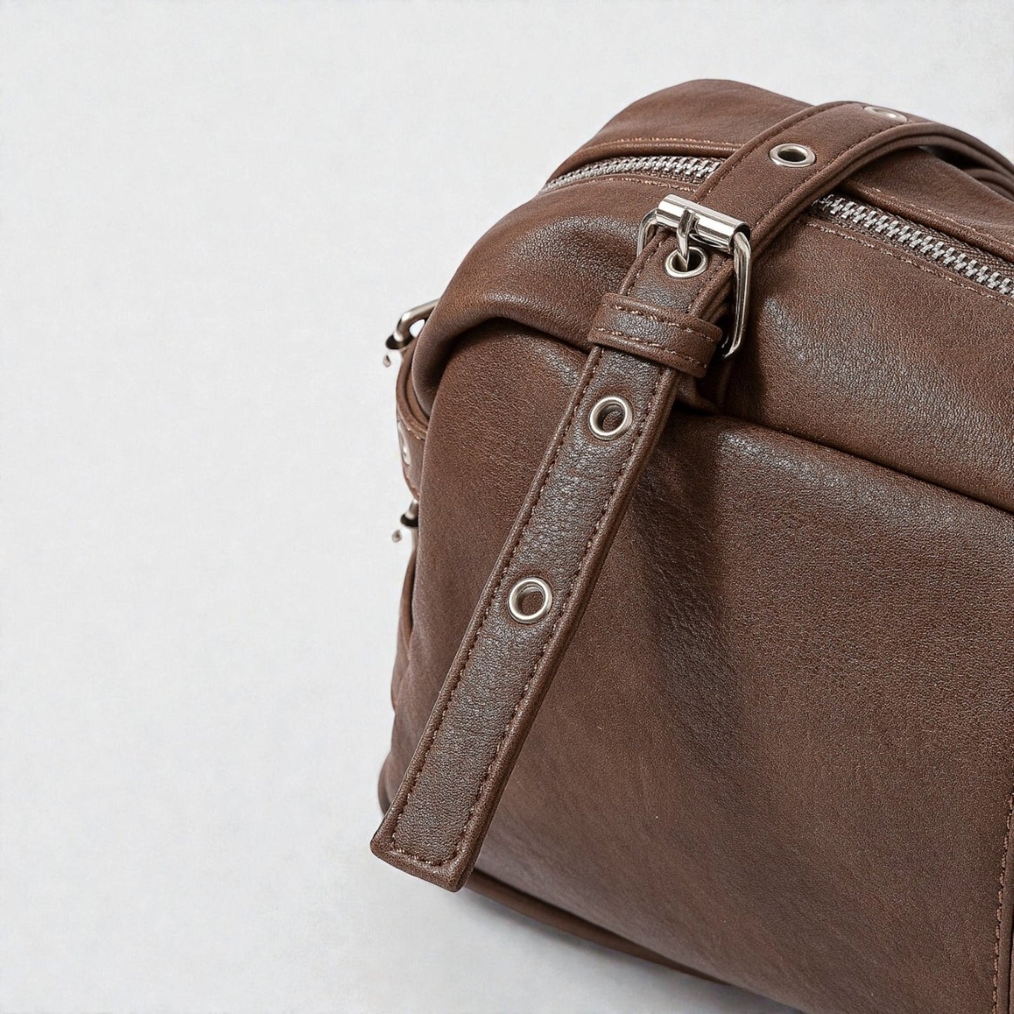 Brown leather bag with a strap on a light gray background