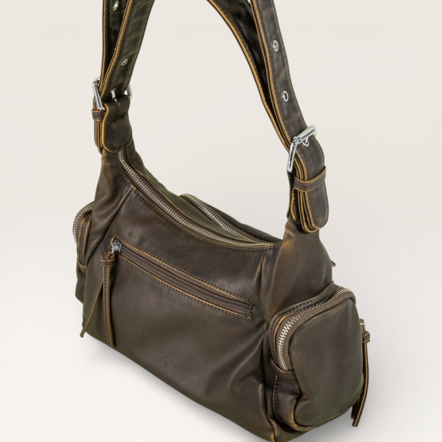Brown leather handbag with multiple zippers on a light gray background