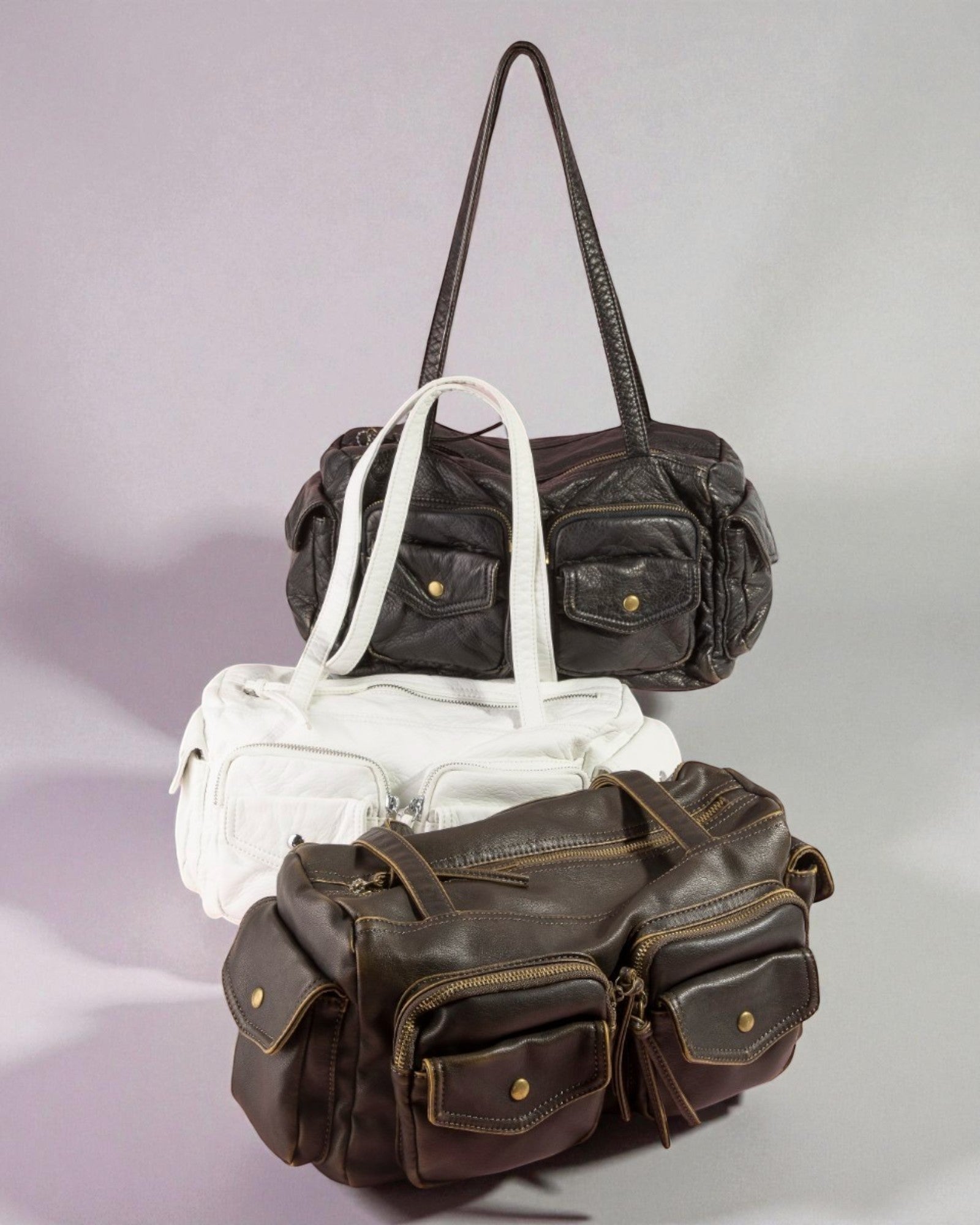 Three leather handbags in different colors on a light gray background