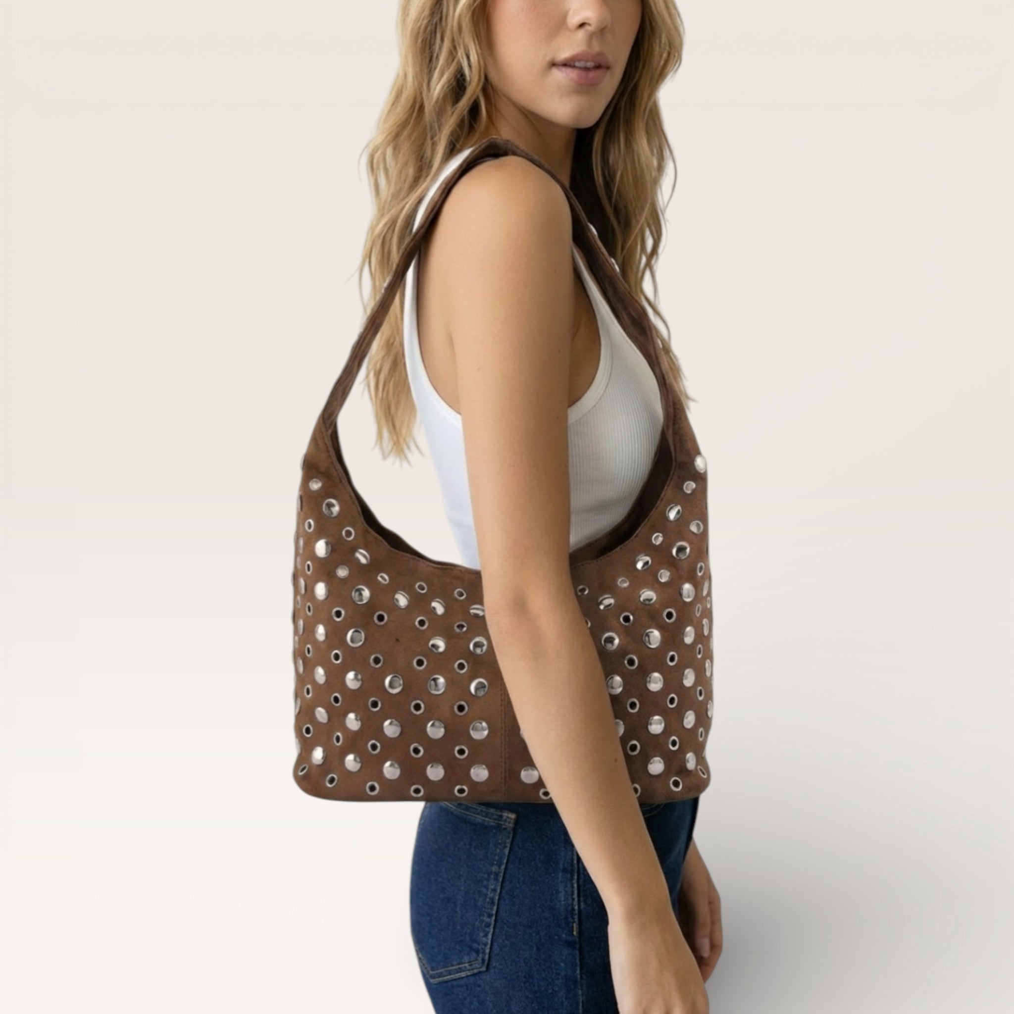 Woman carrying a brown handbag with a unique pattern on a plain background