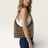 Woman carrying a brown handbag with a unique pattern on a plain background