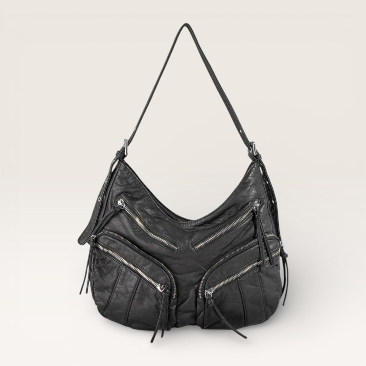 Black leather handbag with zippers on a light gray background