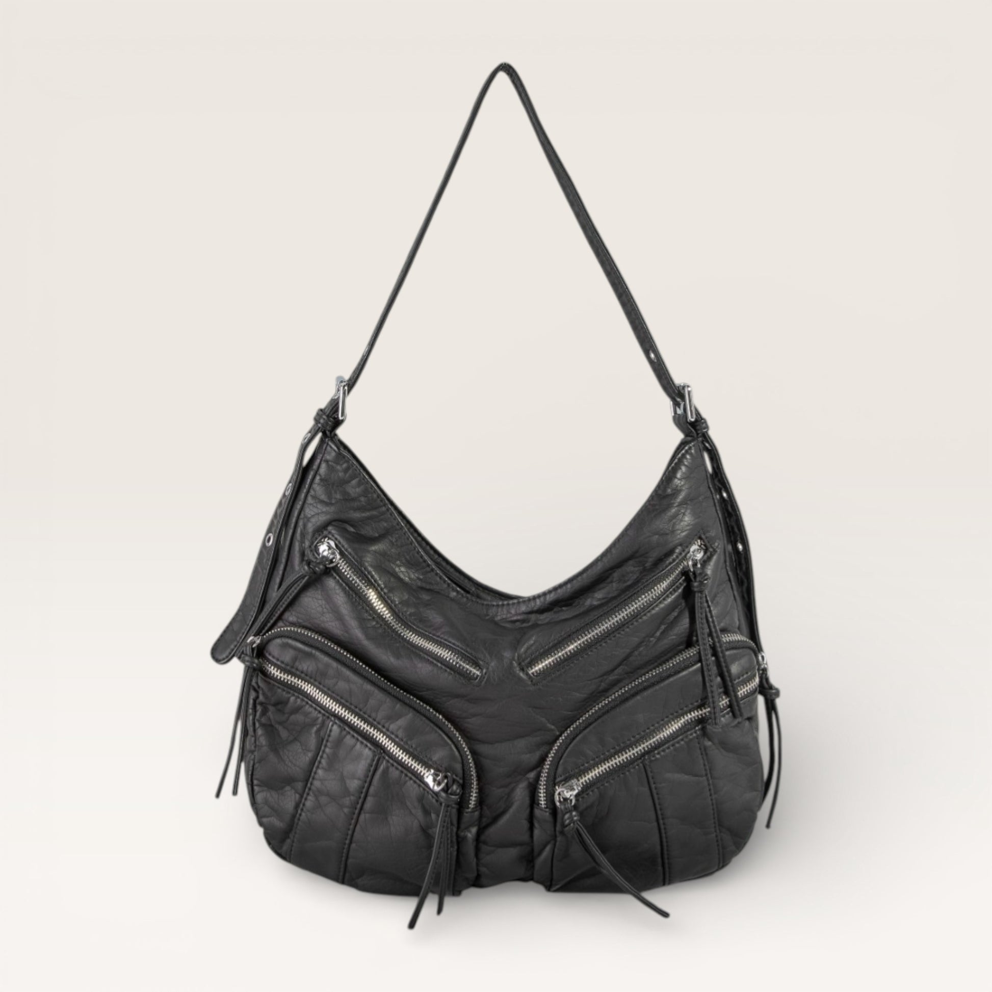 Black leather handbag with zippers on a light gray background
