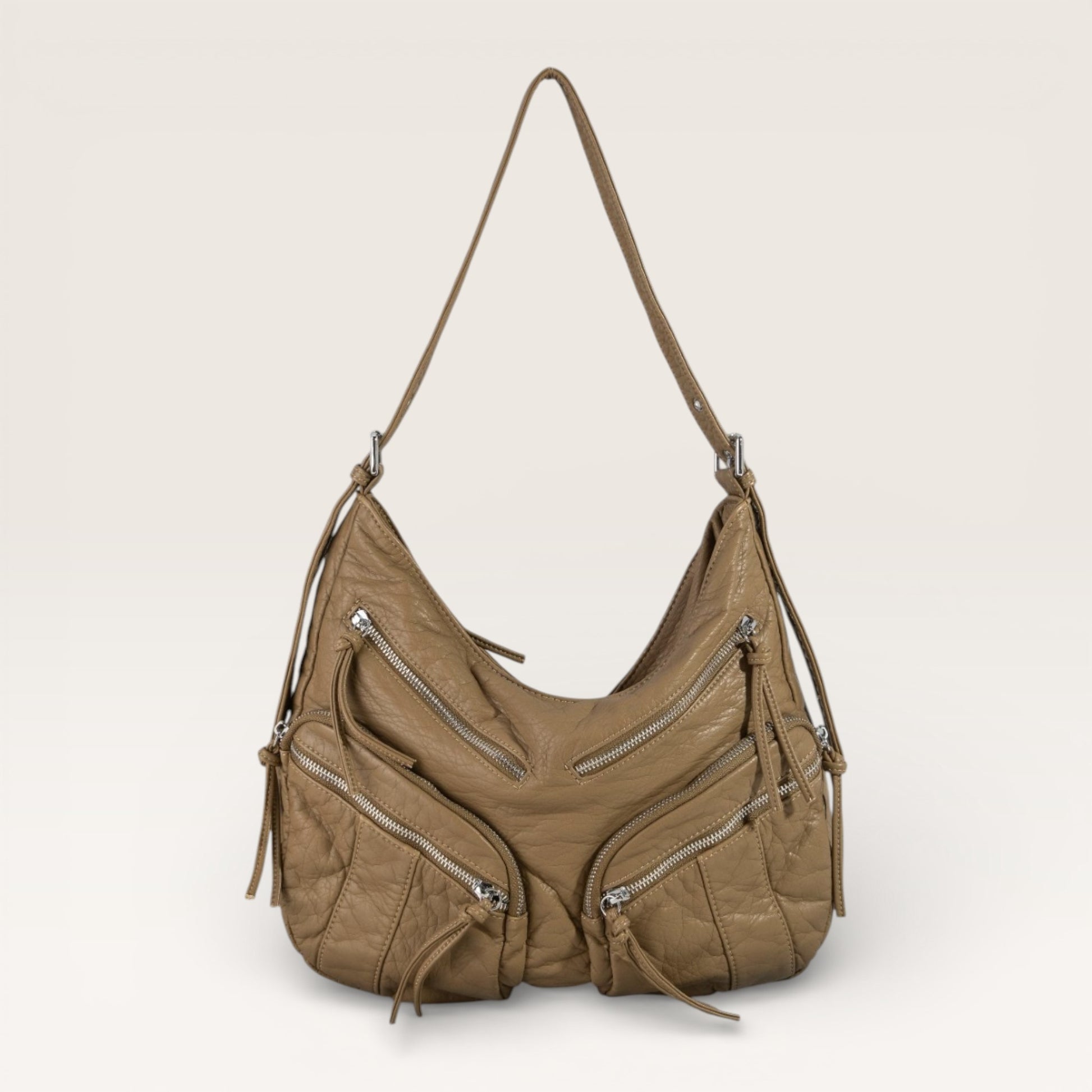 Brown leather handbag with multiple zippers on a beige background