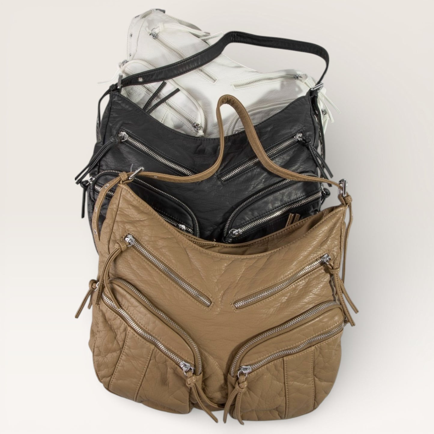 Brown leather handbag with multiple zippers on a white background