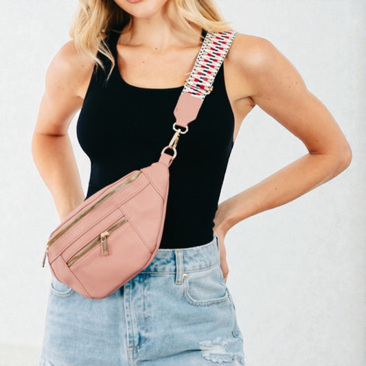 Woman wearing a pink crossbody bag with a colorful strap on a white background