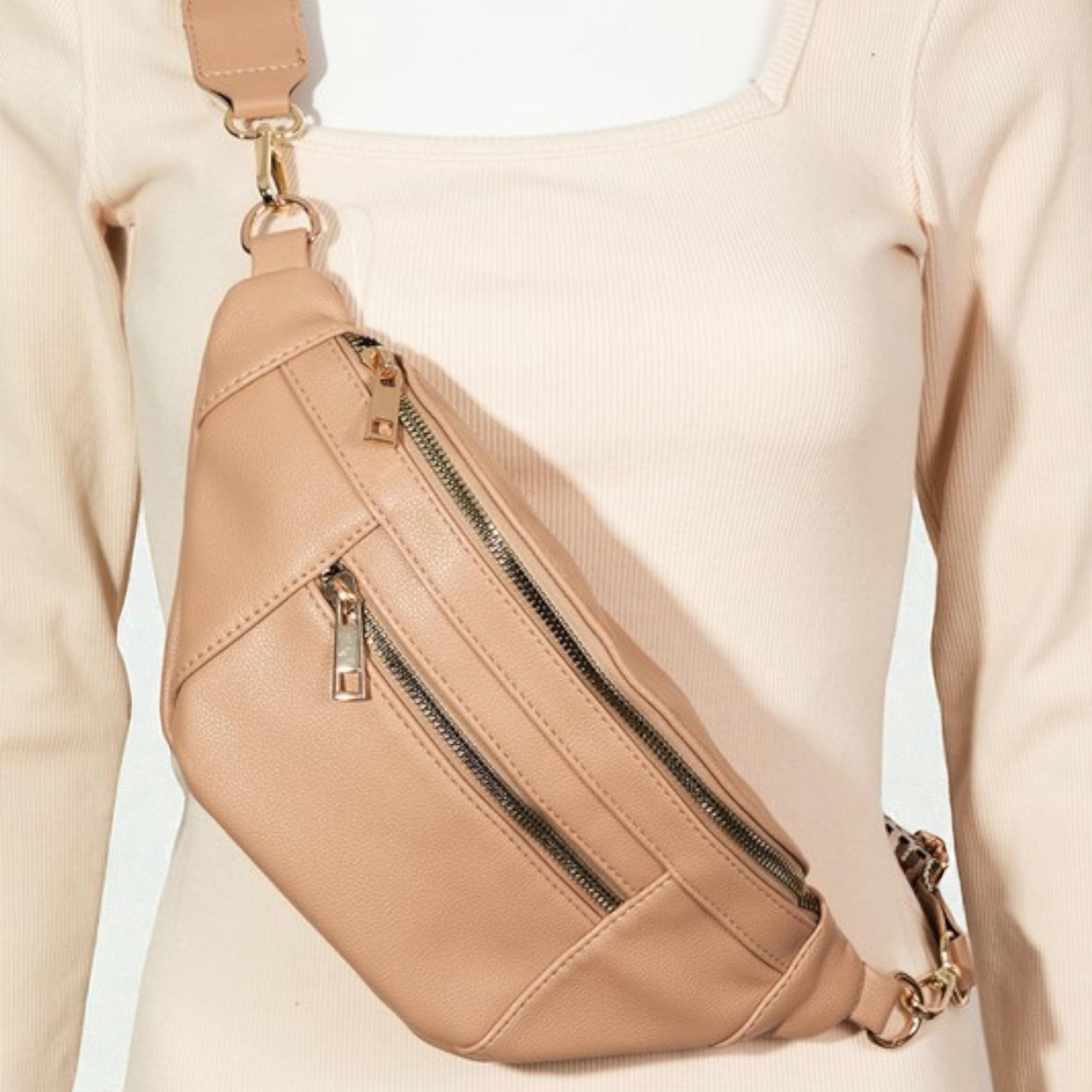 Beige crossbody bag worn by a person on a light beige background