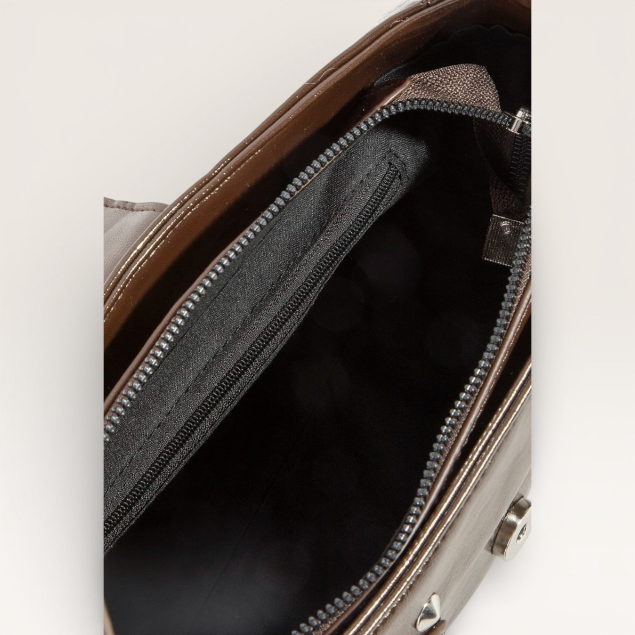 Close-up of a brown leather bag with a zipper, showing the interior.