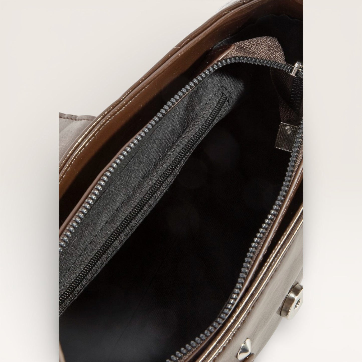 Close-up of a brown leather bag with a zipper, showing the interior.