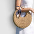 Round woven bag with a scarf over the elbow against a light background