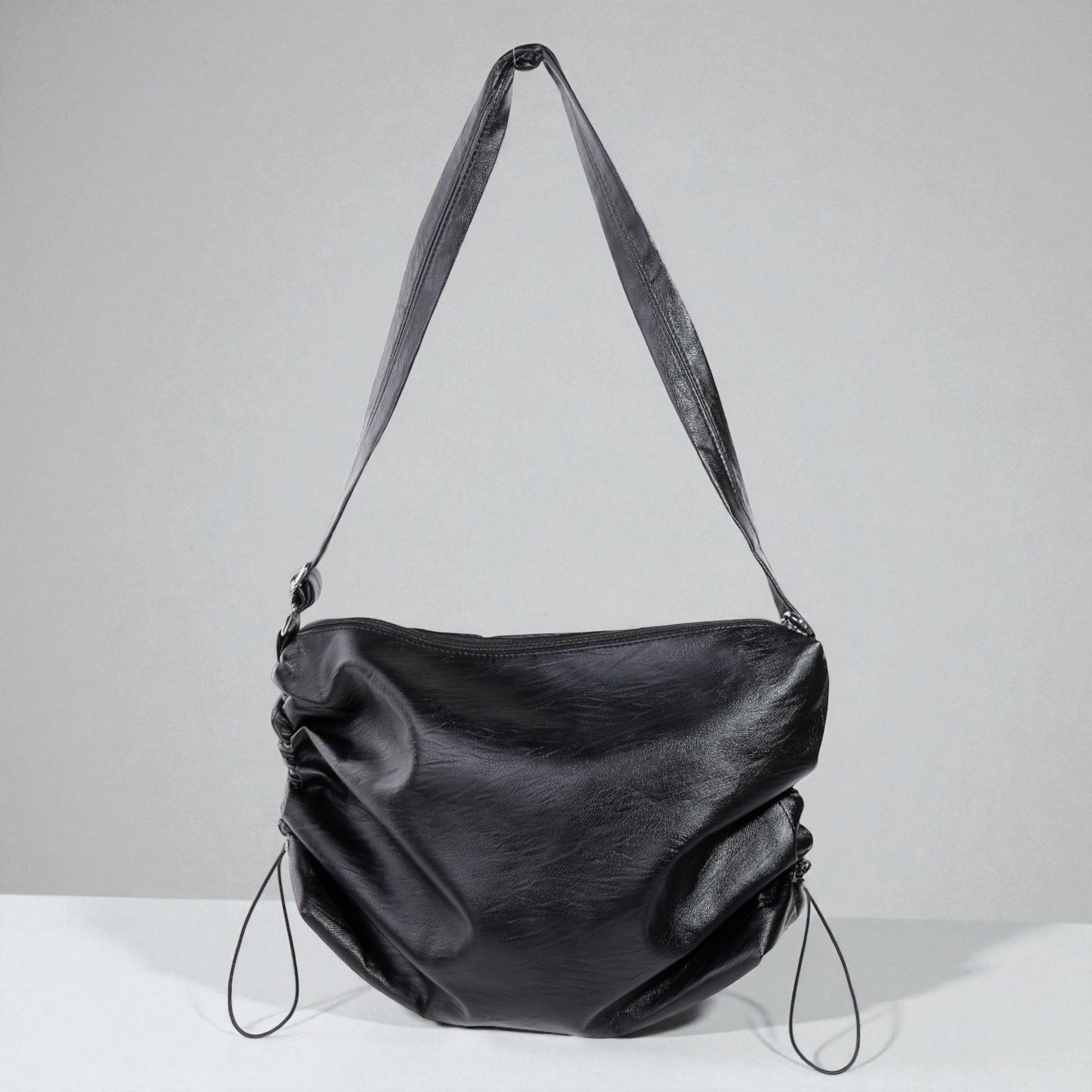 Black leather handbag with a strap on a light gray background