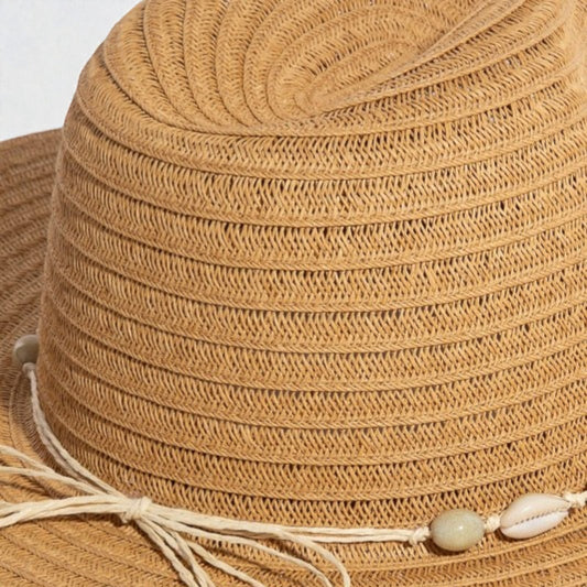 Close-up of a brown straw hat with decorative elements on a light background