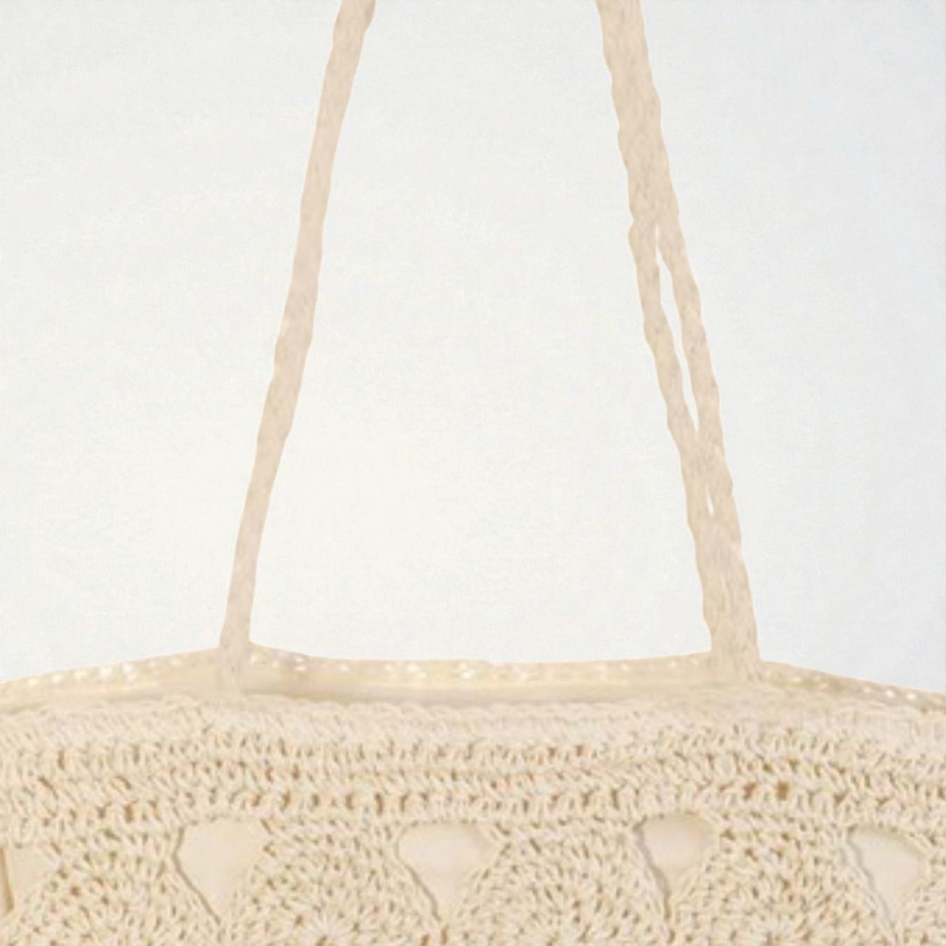 Beige woven handbag with thin handles on a light gray background