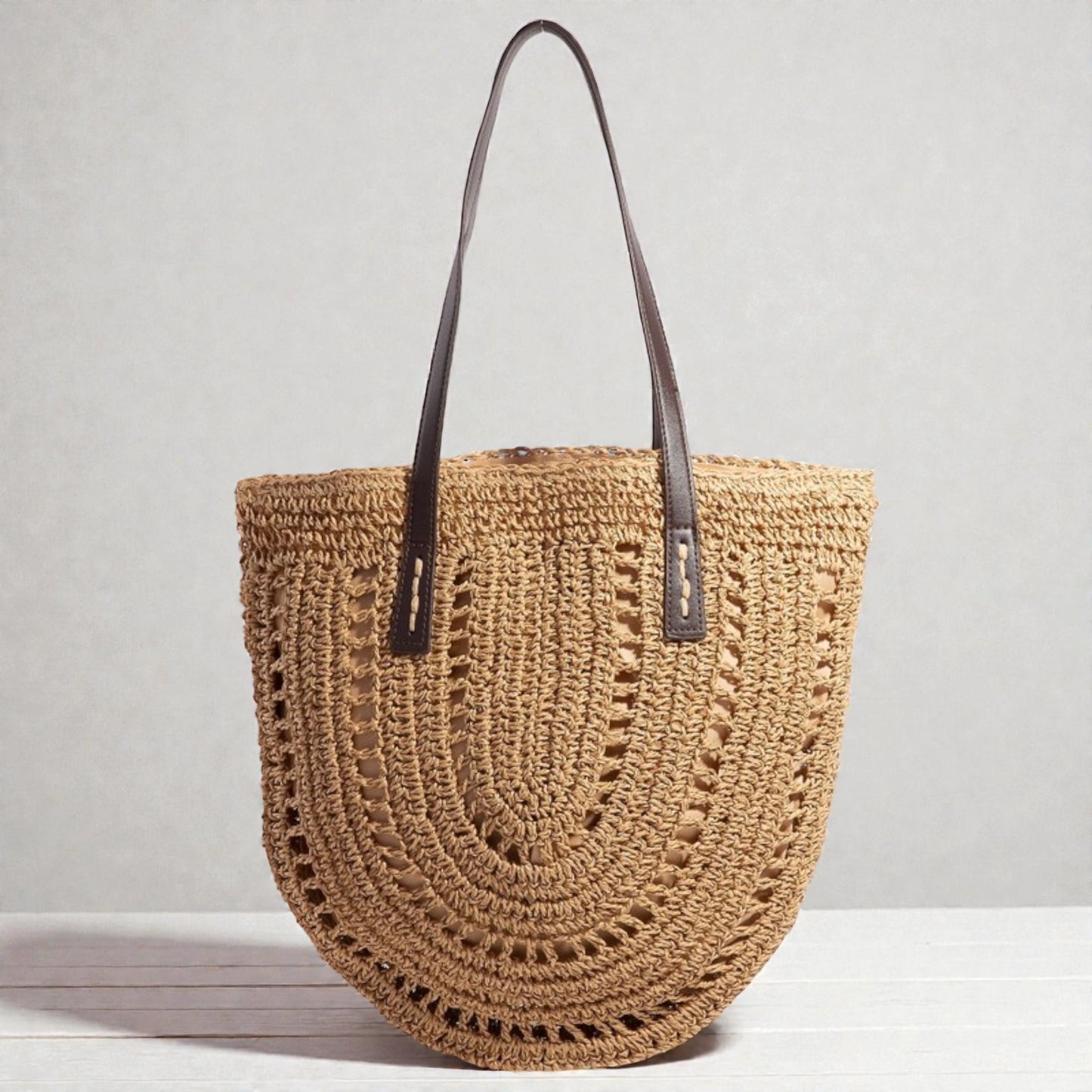 Woven handbag with leather straps on a light gray background
