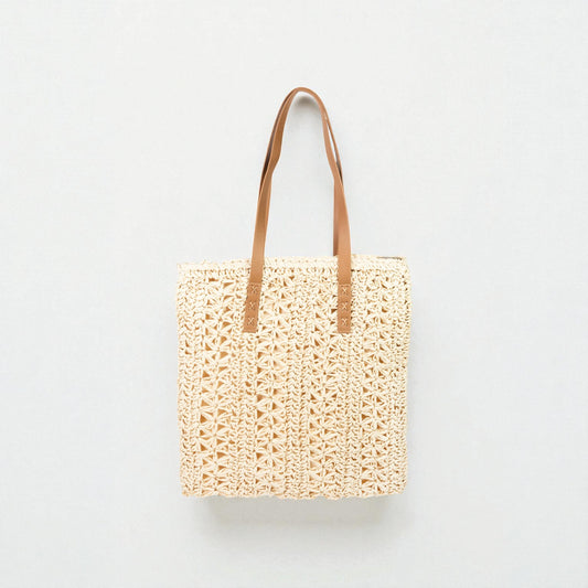 Woven tote bag with brown leather straps on a light gray background