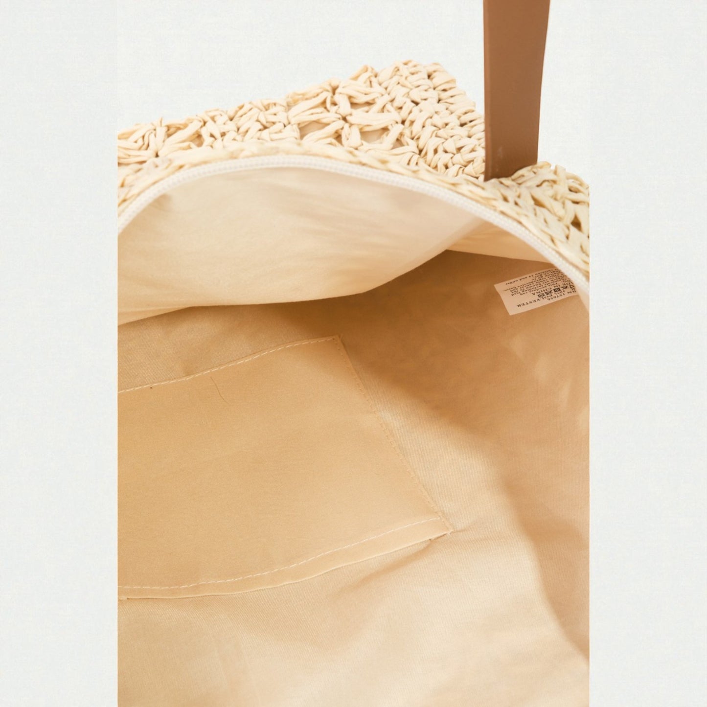 Close-up of a beige woven bag with a visible brand label on a light gray background