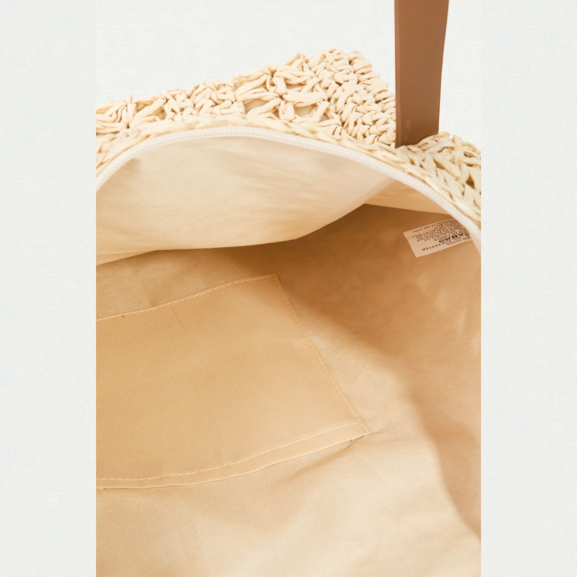 Close-up of a beige woven bag with a visible brand label on a light gray background