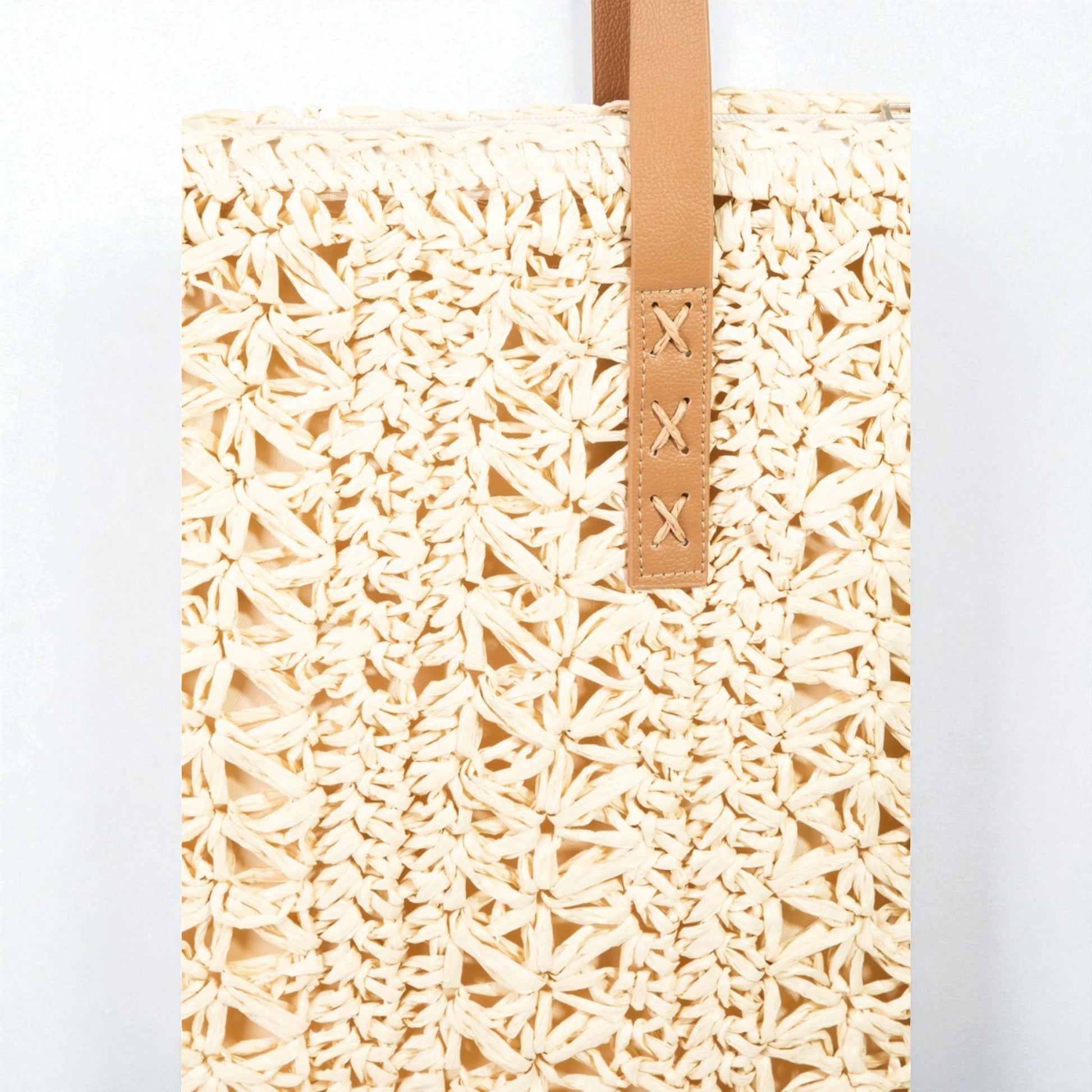 Woven beige tote bag with a brown strap on a white background