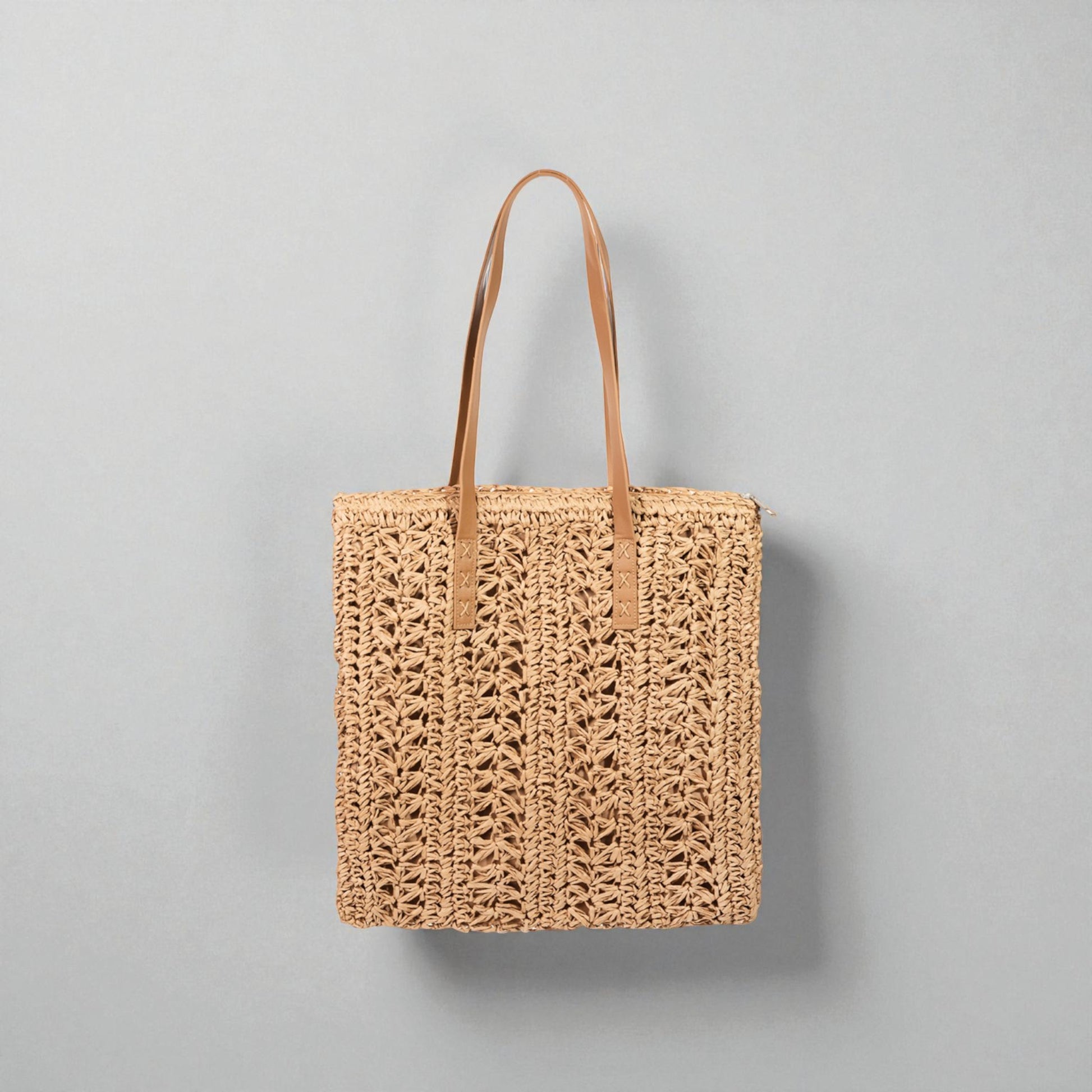 Woven tote bag with leather handles on a gray background