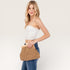 Woman holding a woven clutch bag against a plain background
