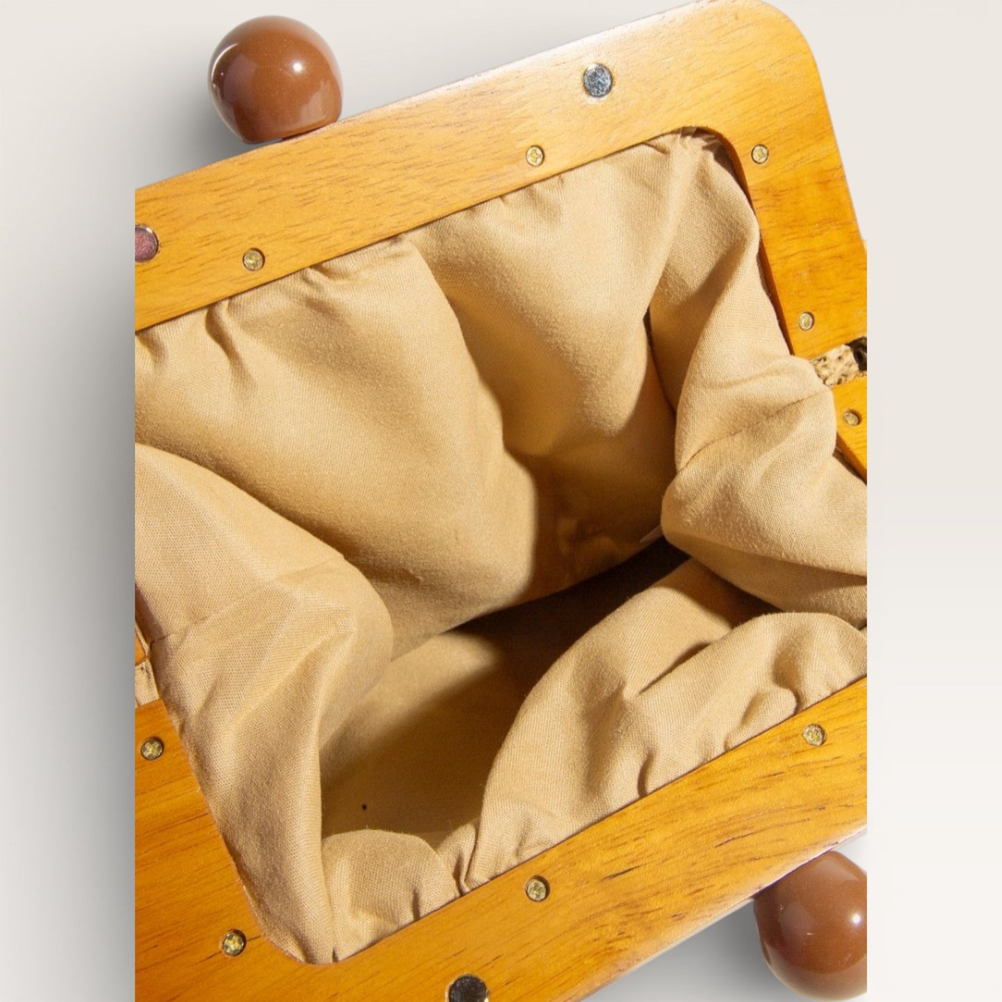 Close-up of a wooden toy with beige fabric interior on a light gray background