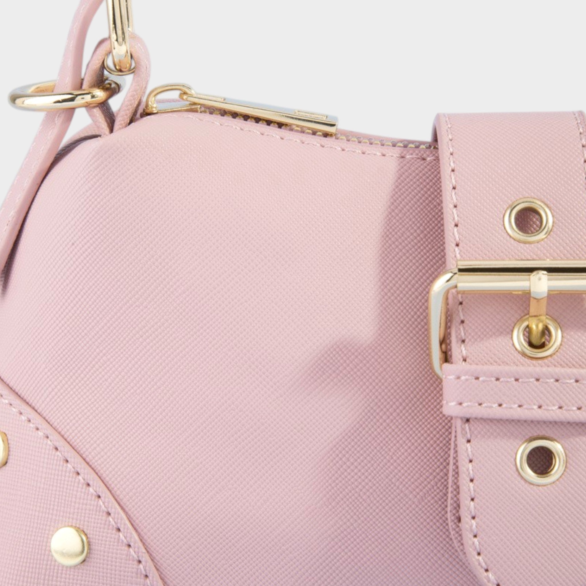 Close-up of a pink handbag with gold accents on a light gray background