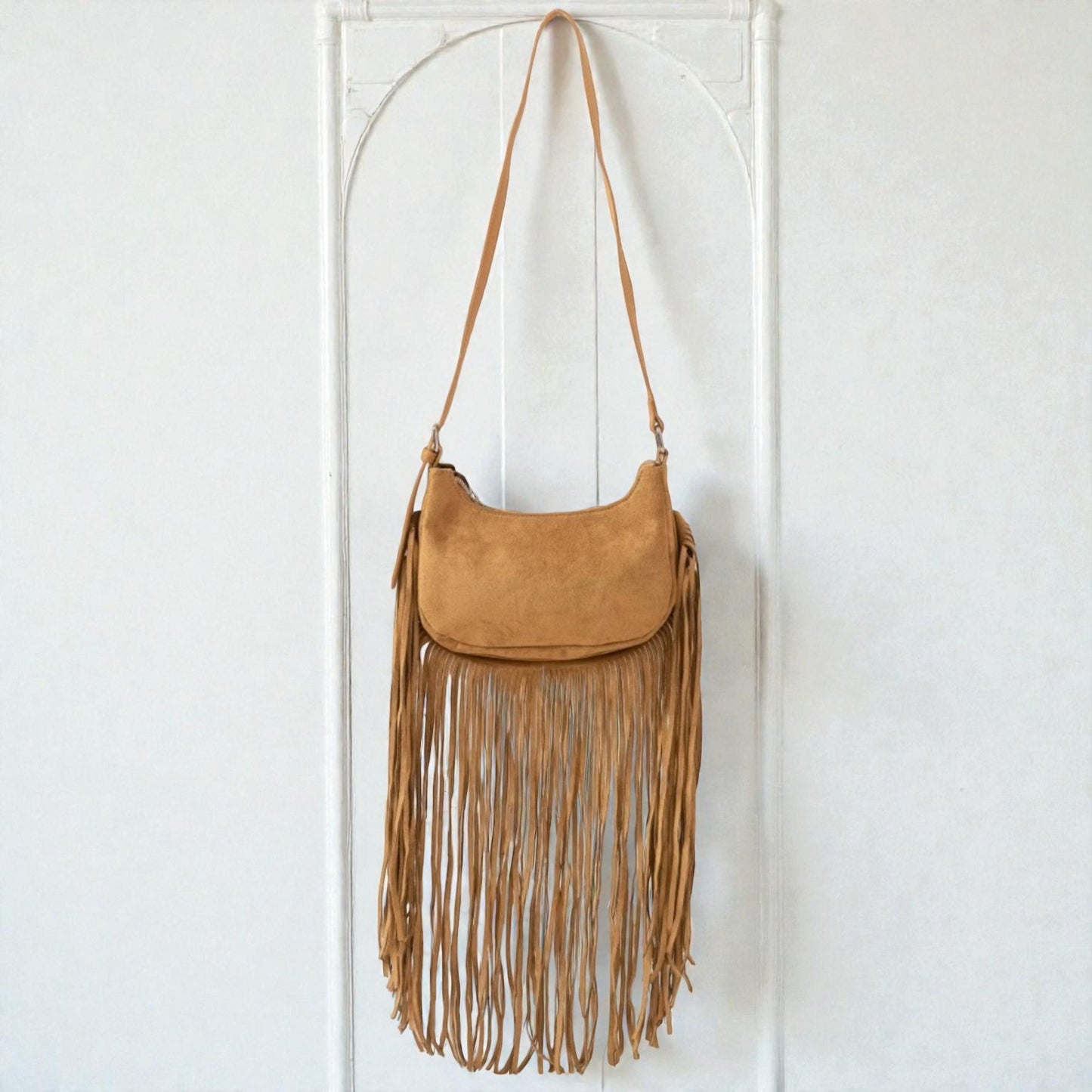 Brown suede handbag with fringe details on a white background