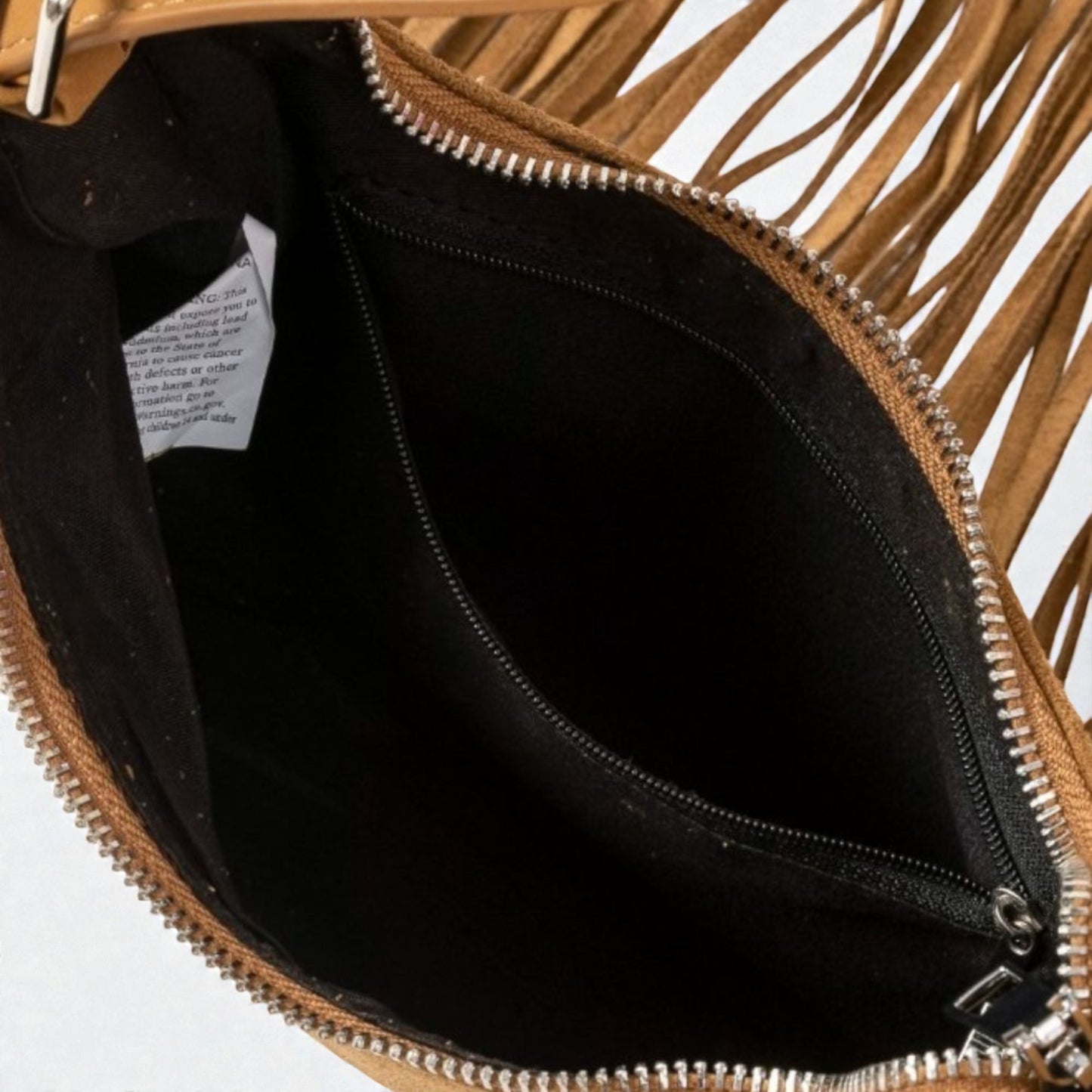 Close-up of a brown leather clutch with fringes and a black interior on a white background.
