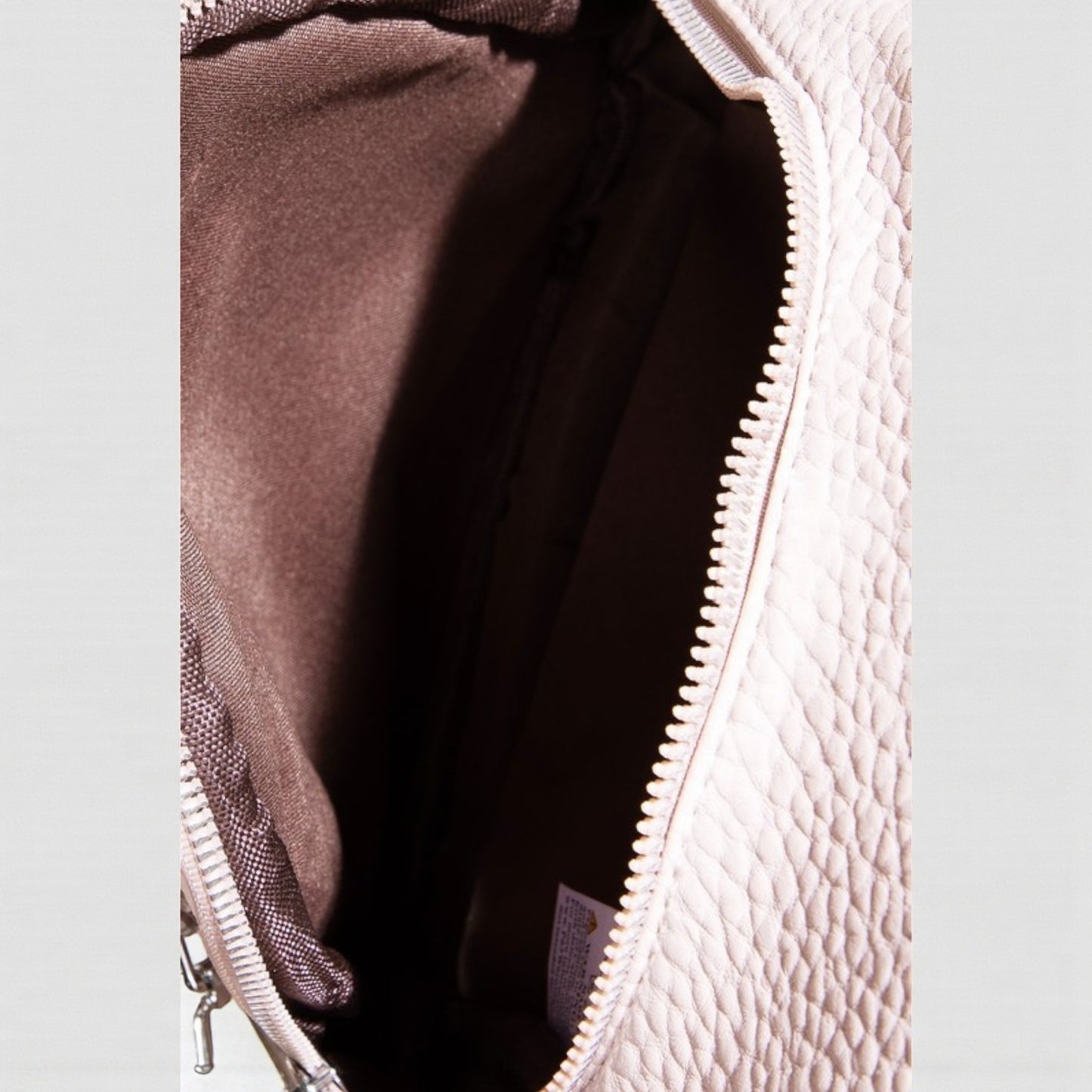 Close-up of a textured bag with a zipper partially open on a light gray background