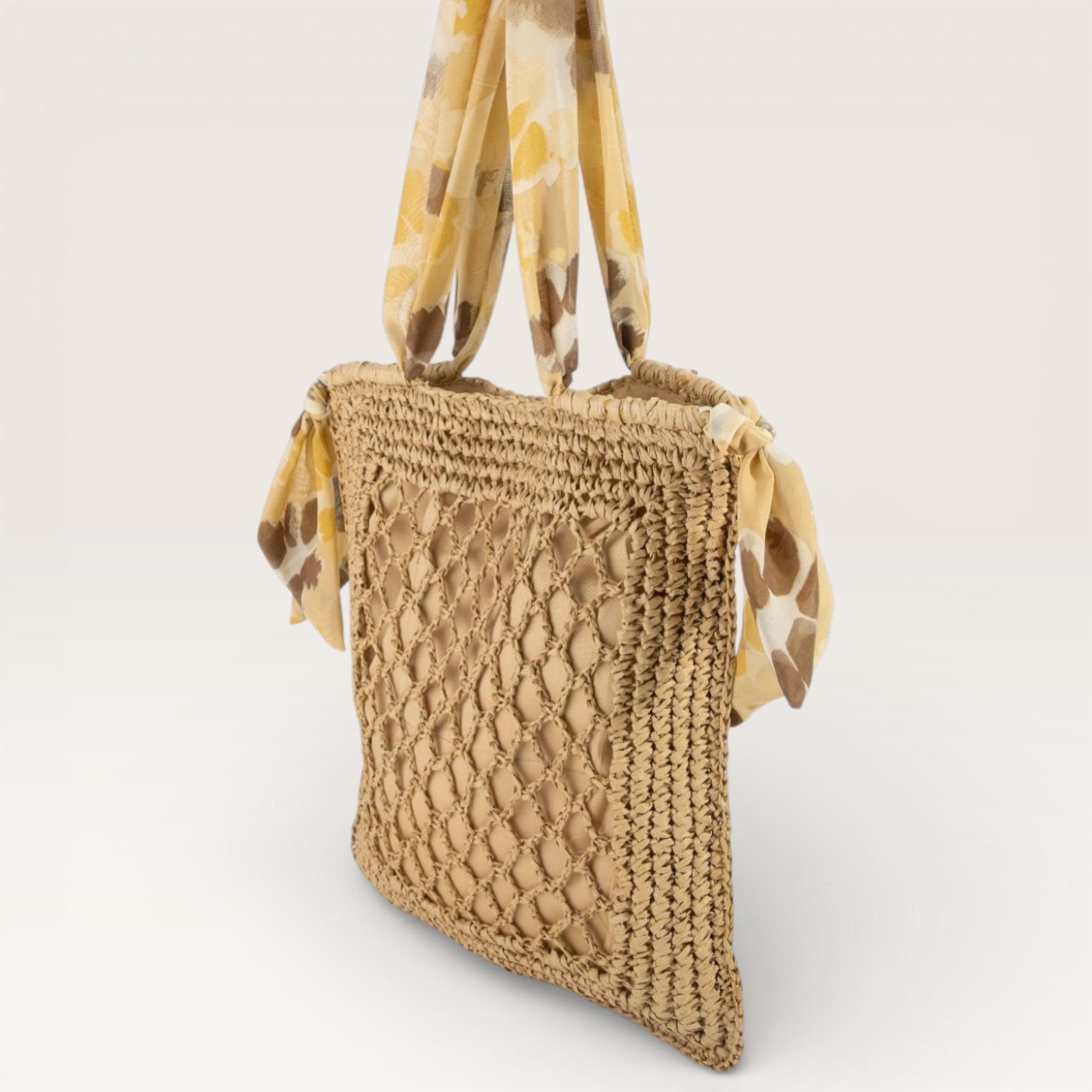 Woven straw handbag with patterned strap on a light background