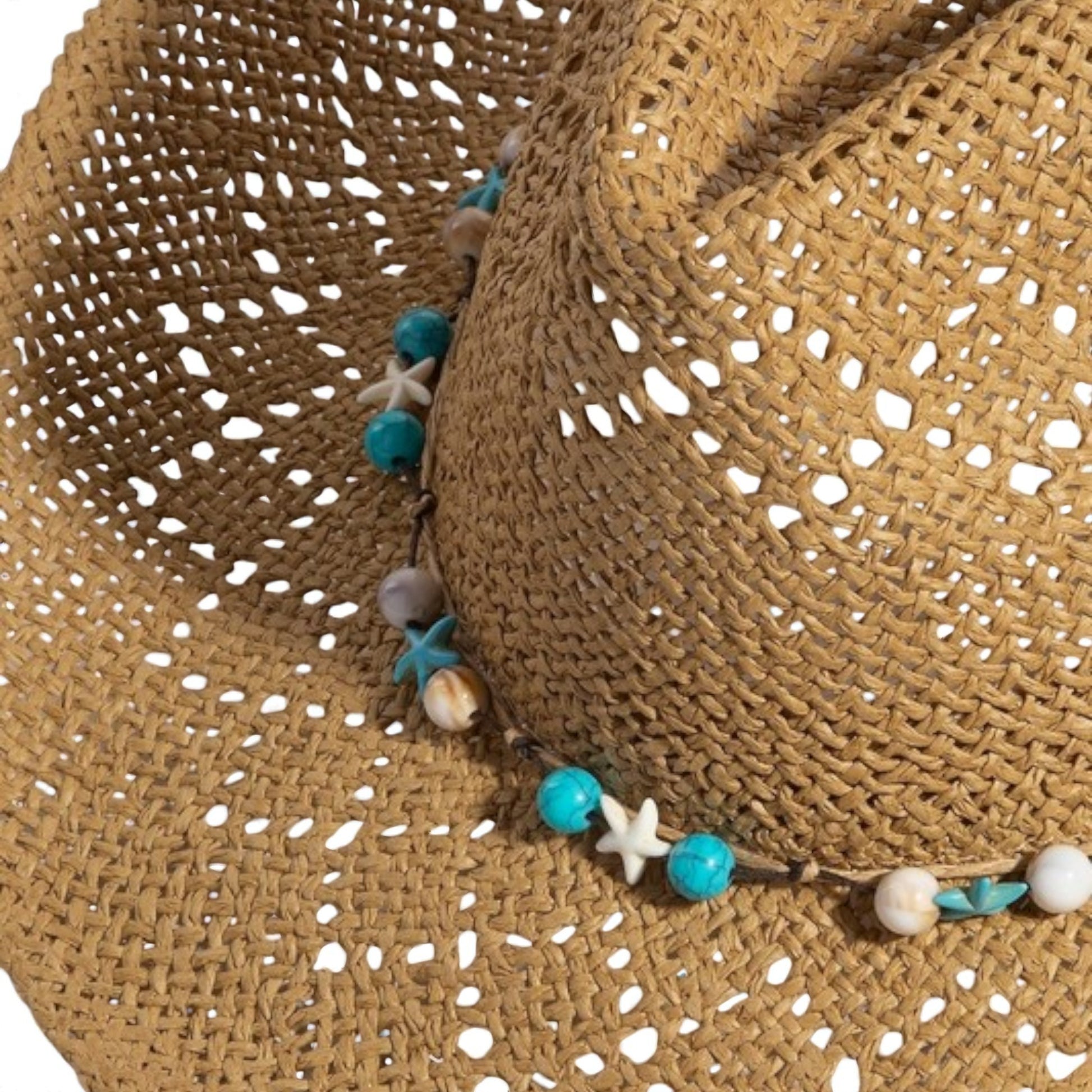 Close-up of a straw hat with decorative beads and starfish on a white background