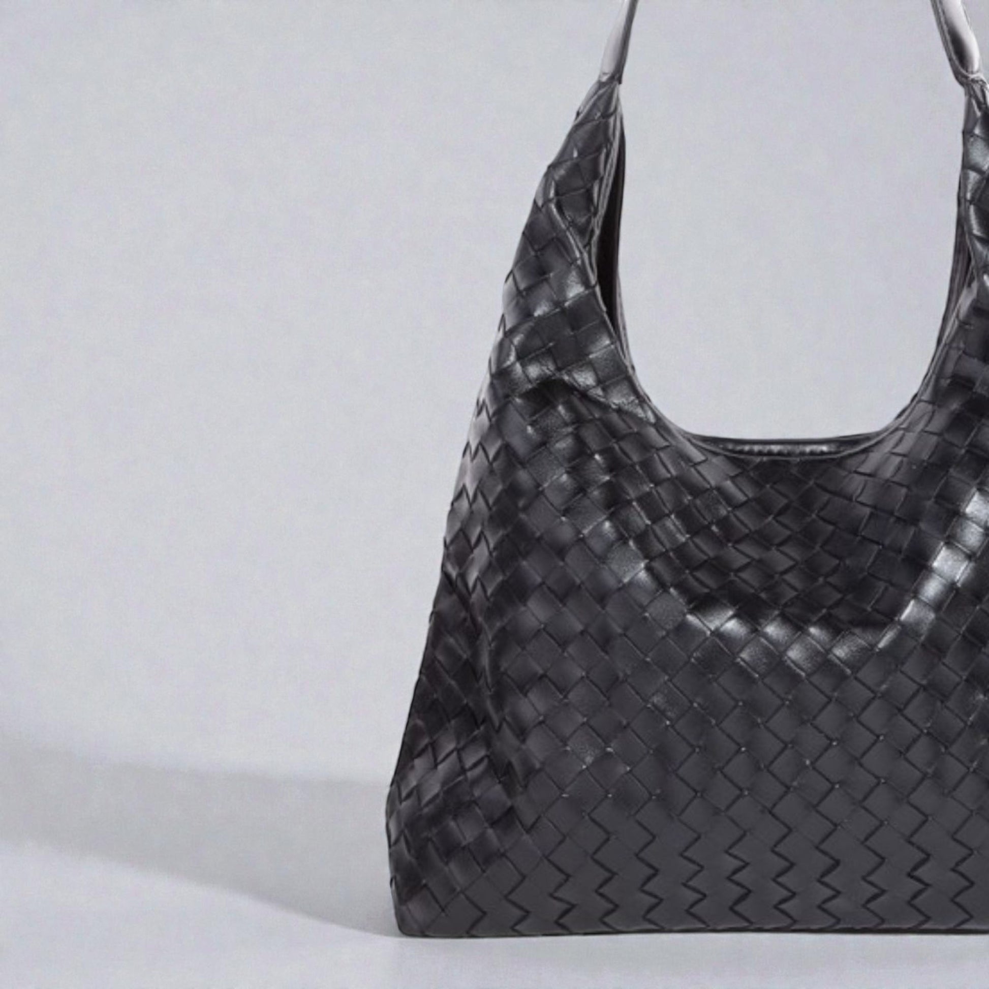 Black woven handbag on a light gray background