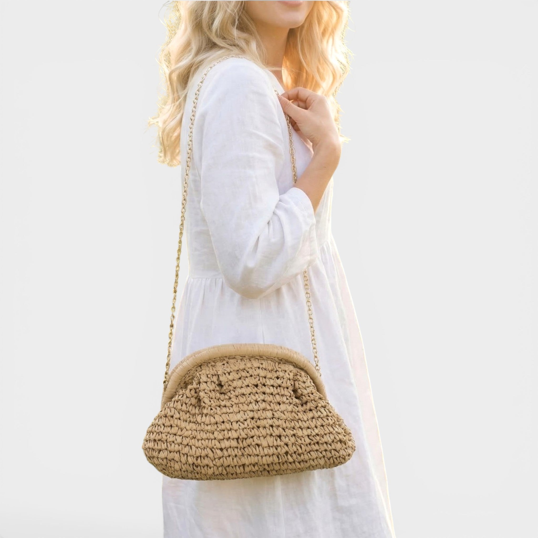Woman holding a woven handbag against a plain background