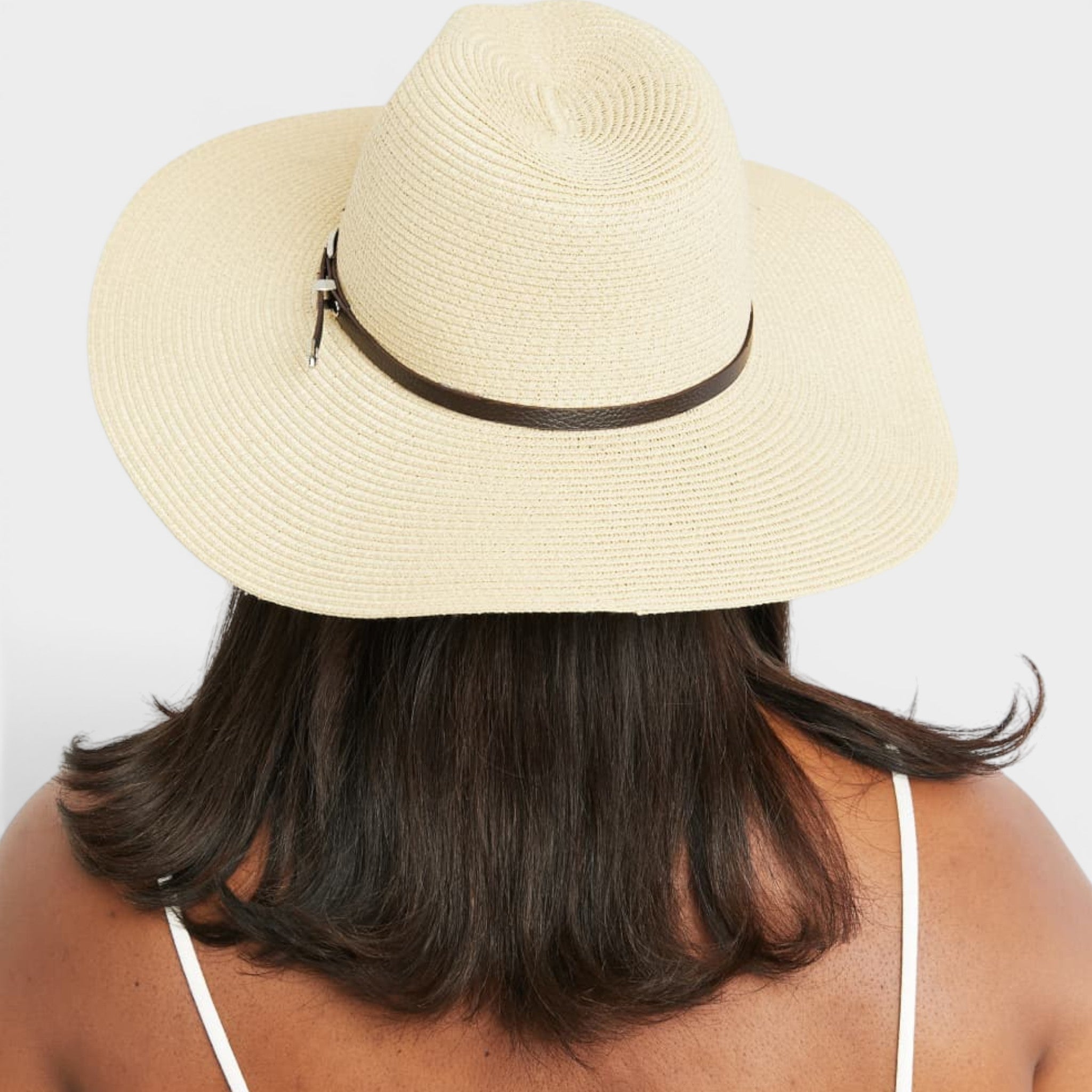 Beige straw hat worn by a person on a plain background