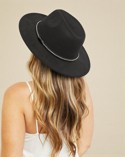 Person wearing a black fedora hat with a beige background