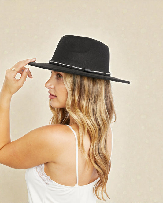 Woman wearing a black fedora hat with a beige background