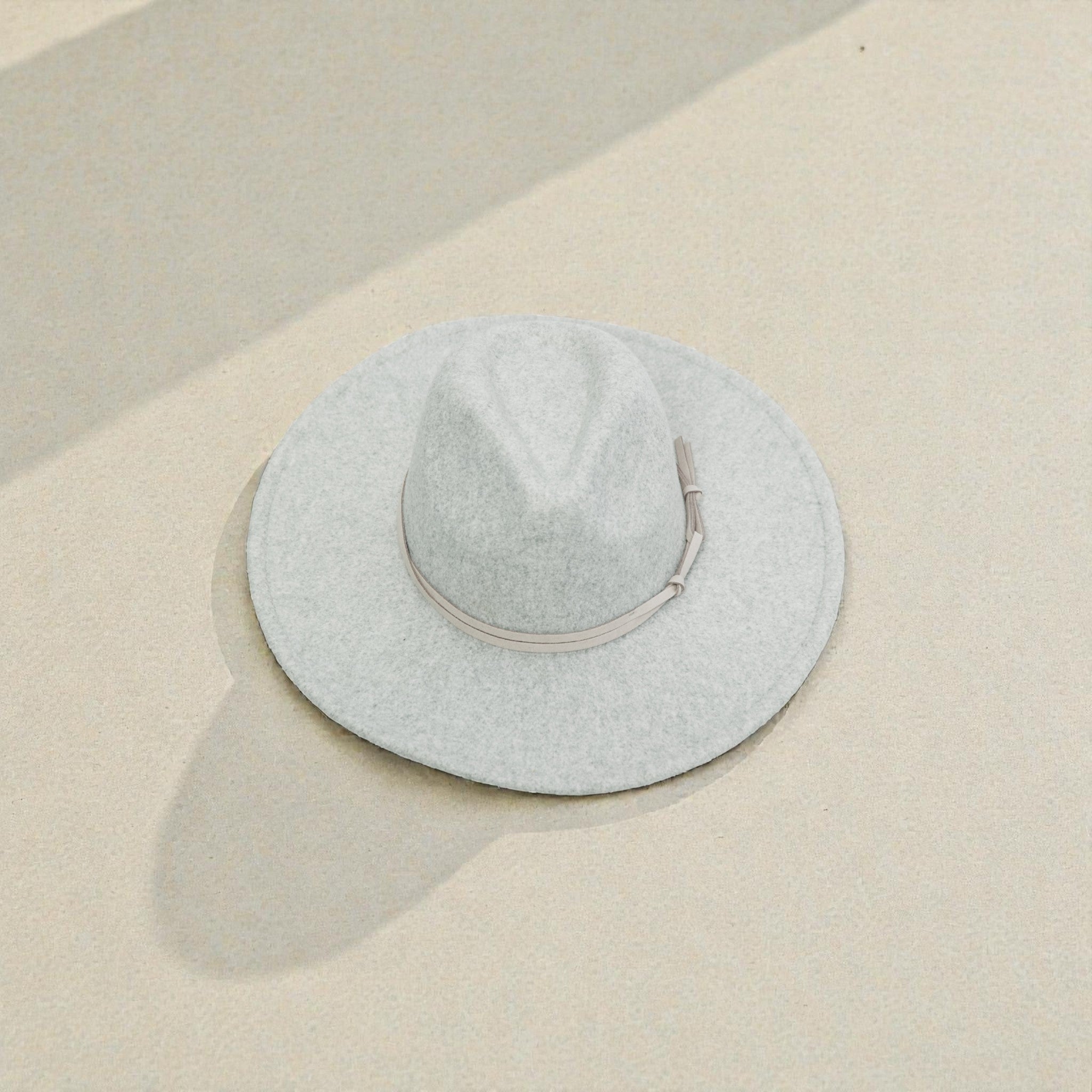 Light gray wide-brimmed hat on a beige surface