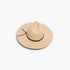 A light beige wide-brim fedora hat with a black band and tie detail, photographed from a top-down angle on a clean white background.