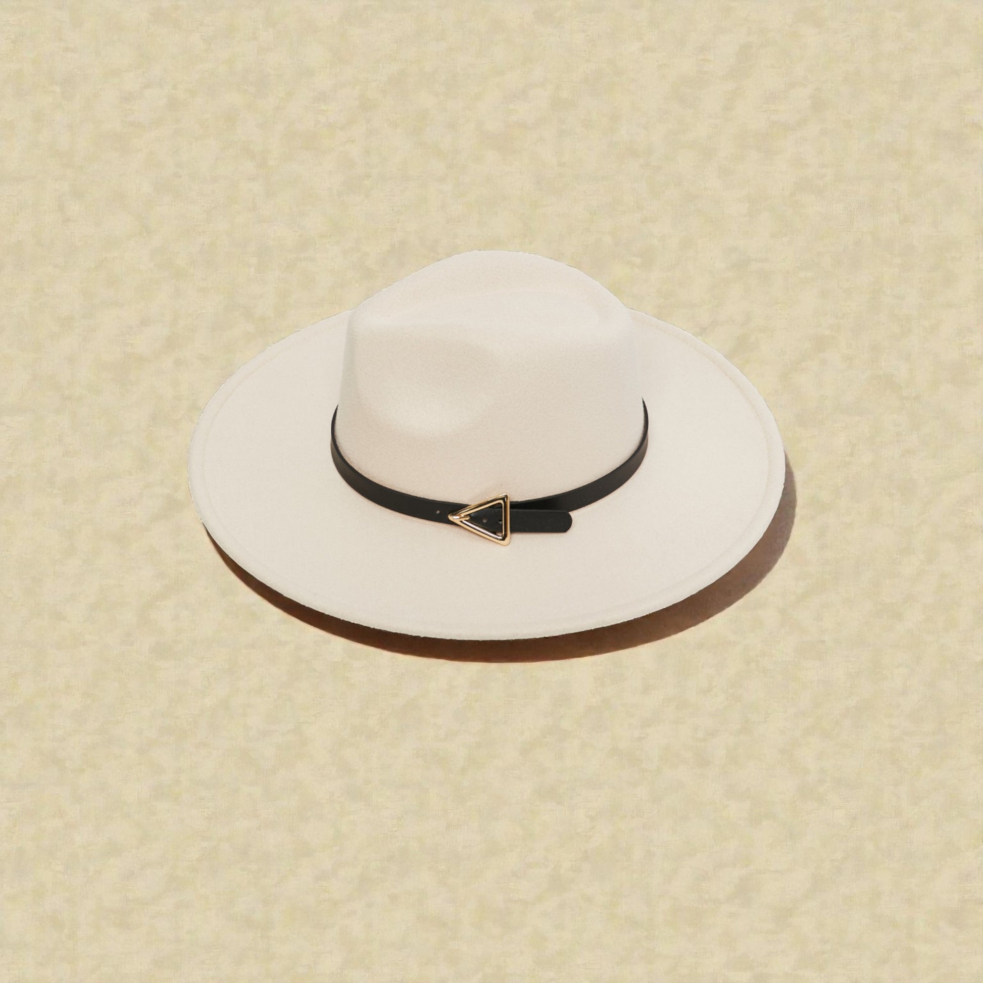 White wide-brimmed hat with a black band featuring a gold triangle on a beige background