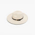 An off-white fedora hat with a black band and a small gold triangular buckle, photographed on a clean white background.