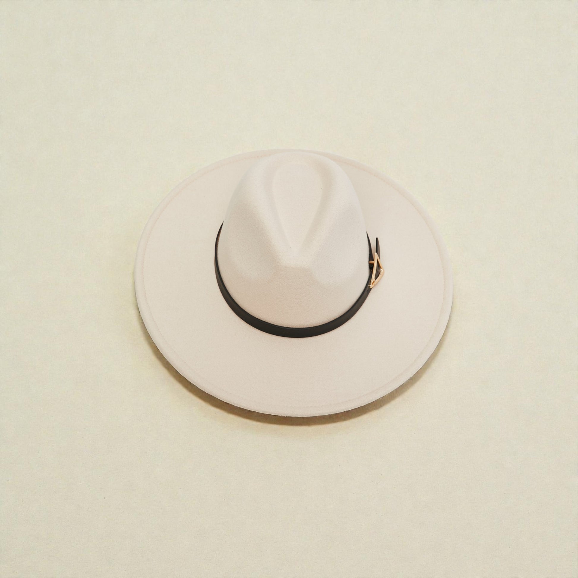White fedora hat with a black band on a beige background