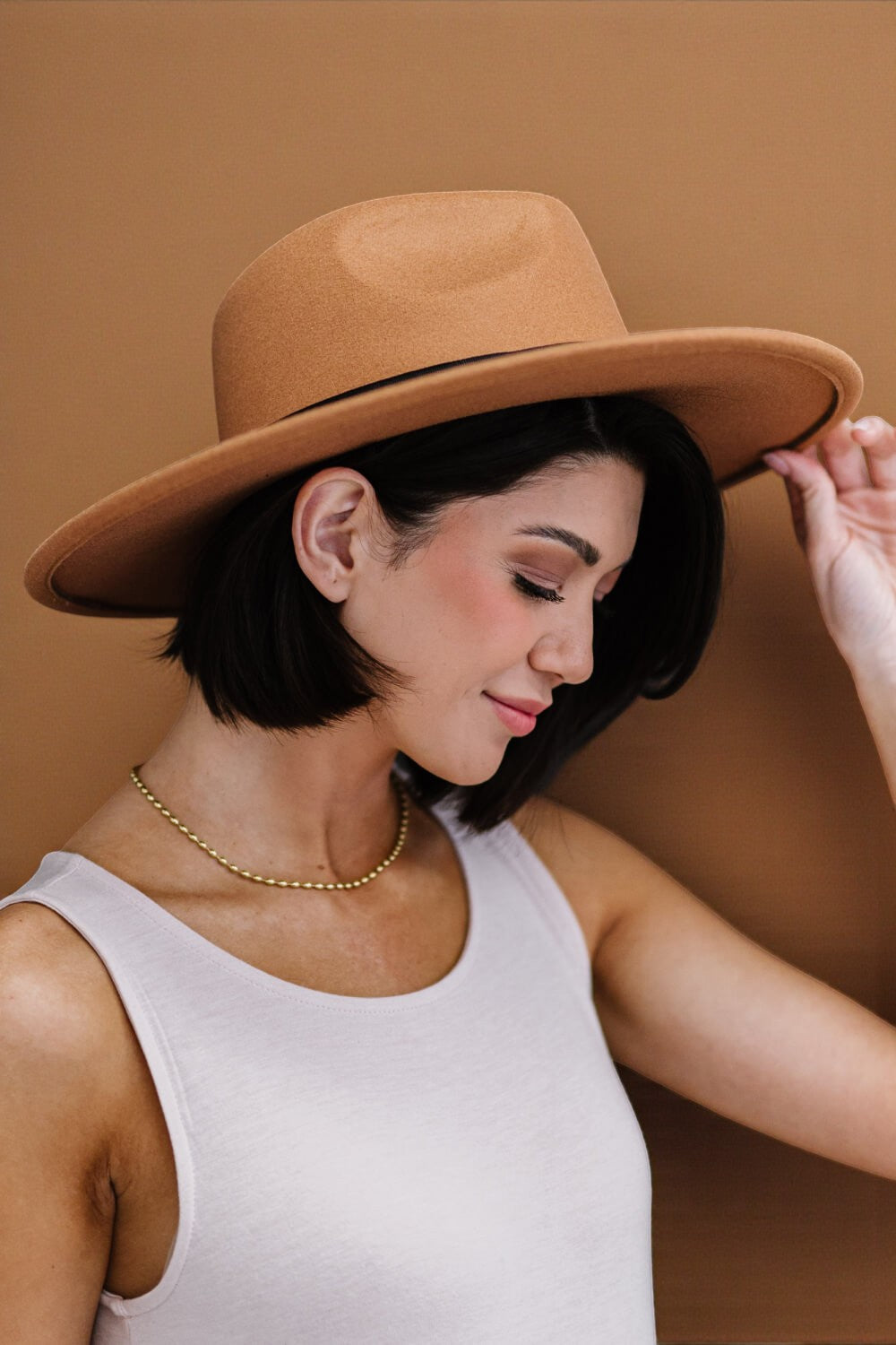 Woman wearing a brown hat against a brown background