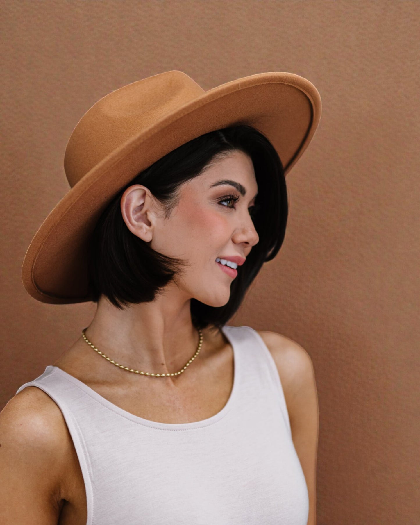 Woman wearing a brown hat against a brown background