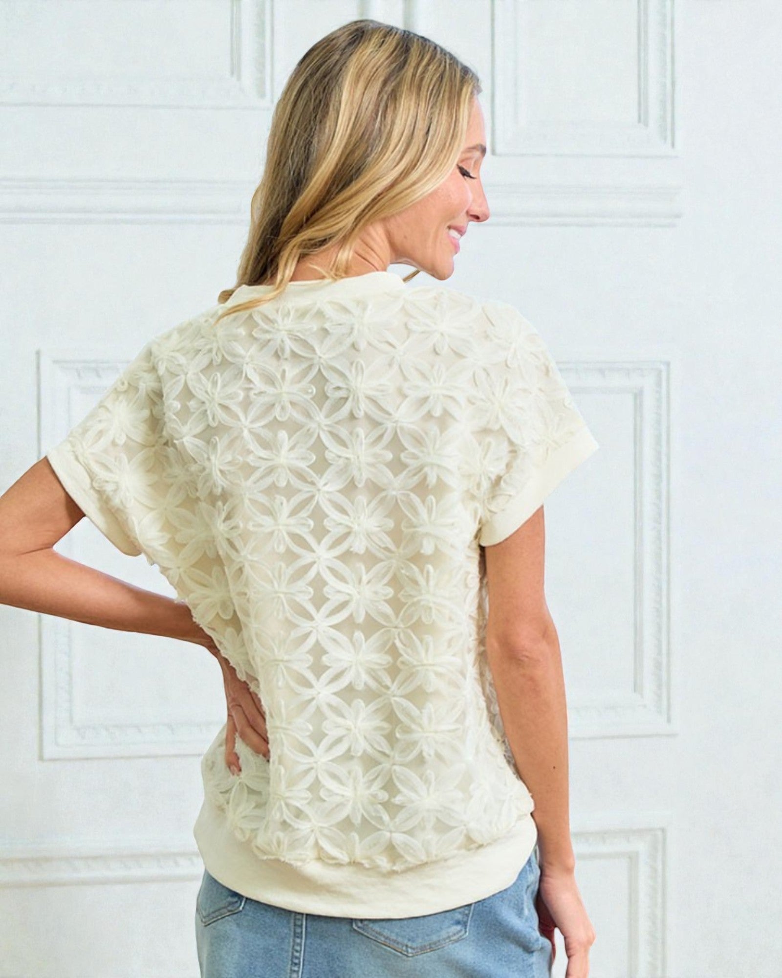 Woman wearing a cream-colored lace top against a white background
