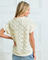 Woman wearing a cream-colored lace top against a white background