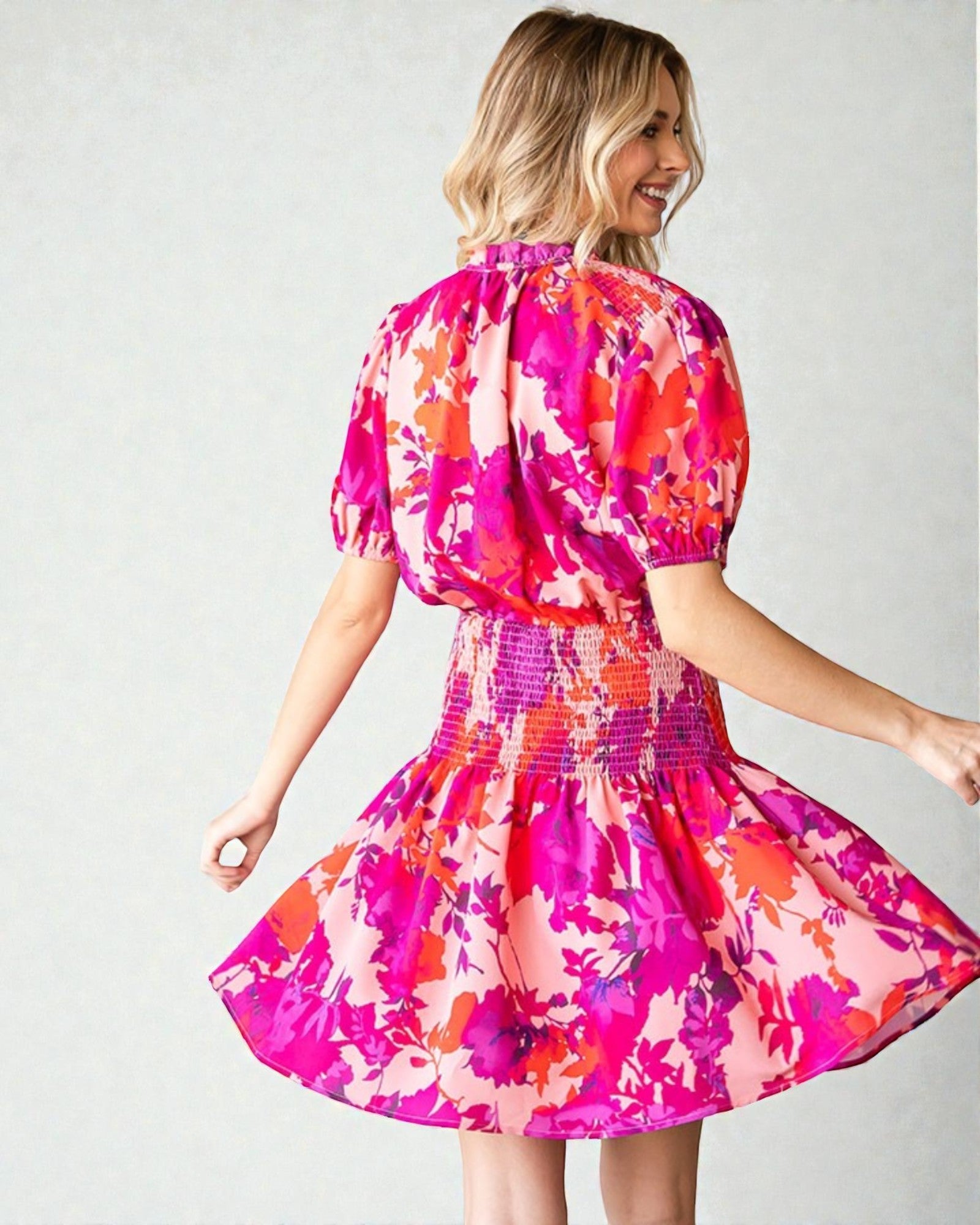 Woman wearing a colorful floral dress against a plain background