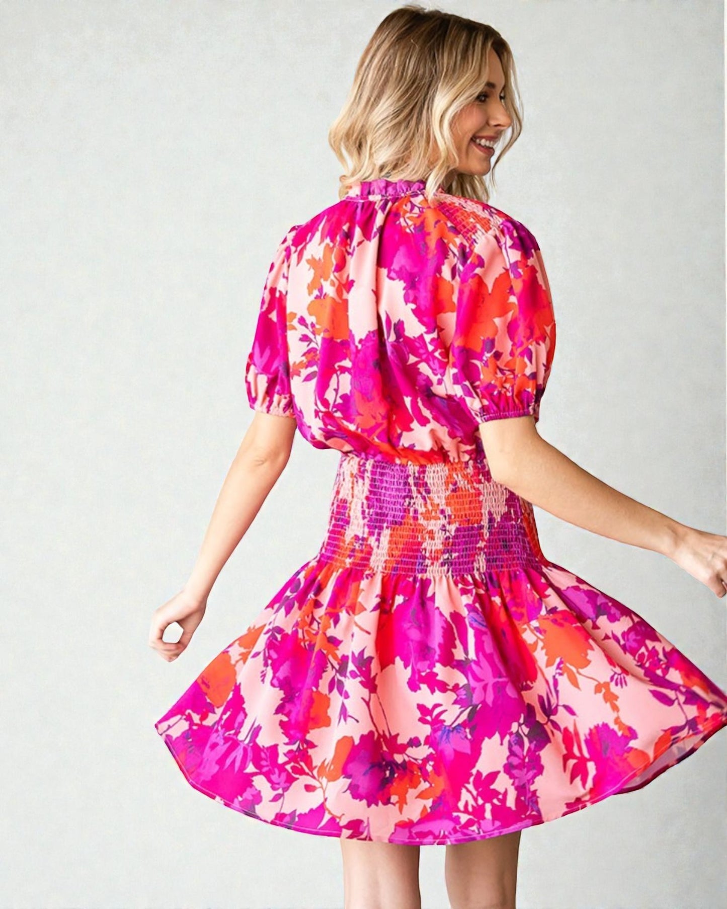 Woman wearing a colorful floral dress against a plain background