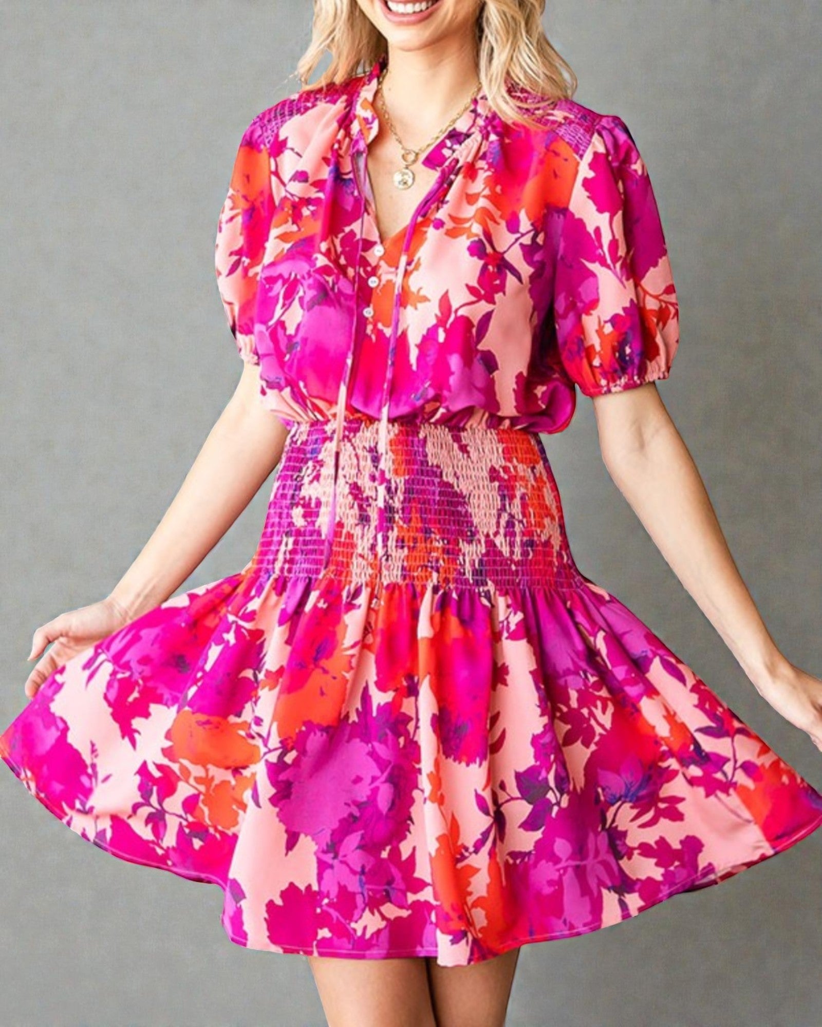 Woman wearing a colorful floral dress against a gray background