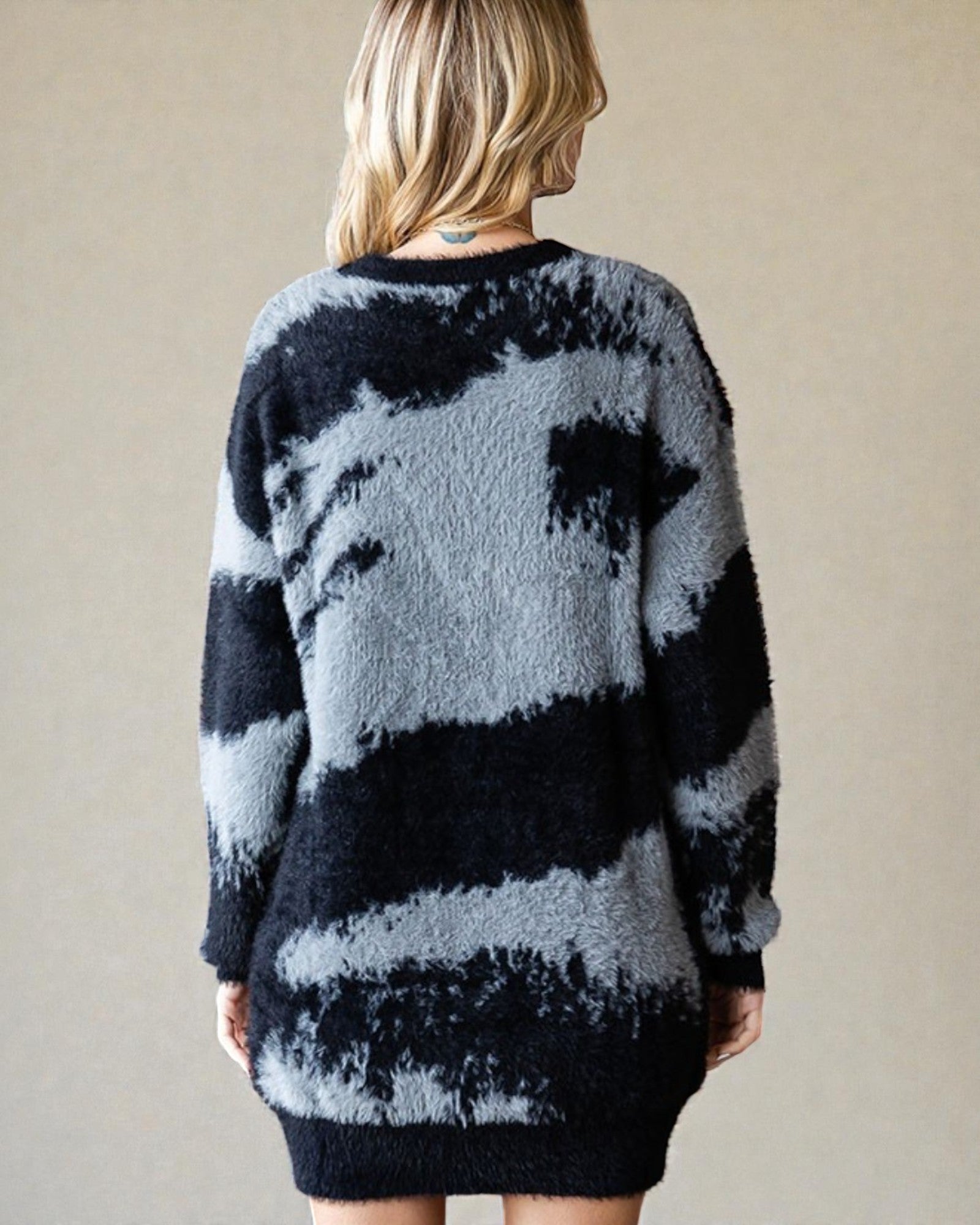 Person wearing a black and gray tie-dye sweater against a plain background