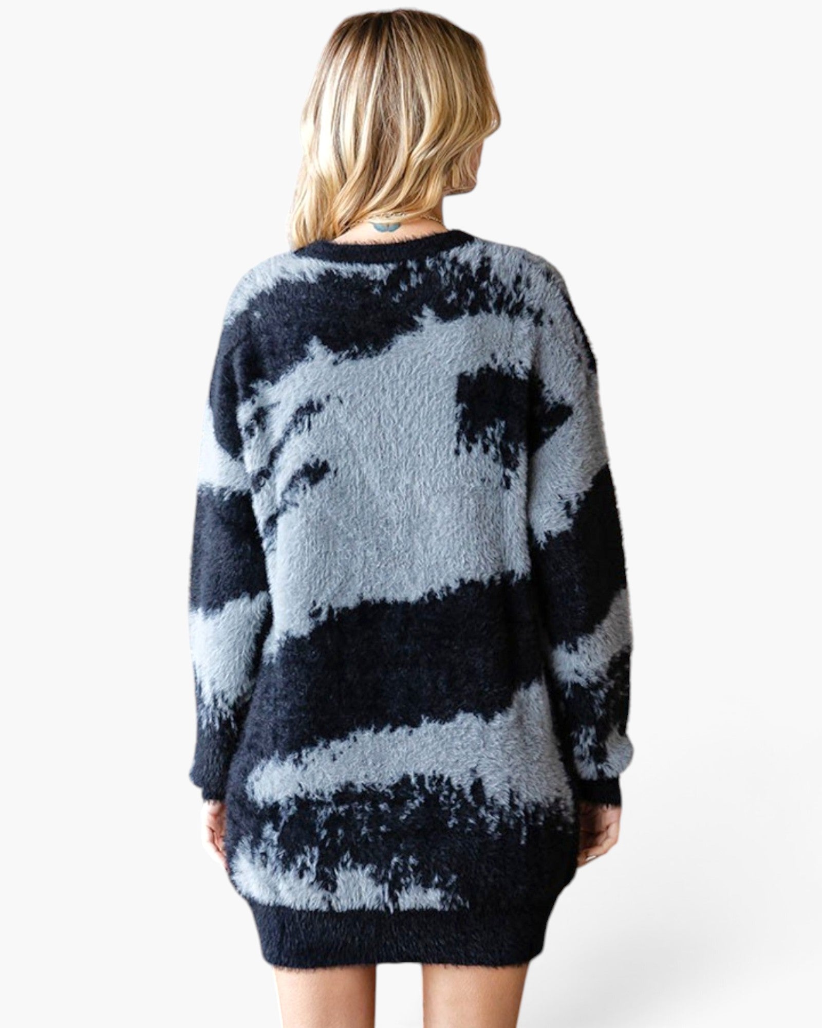 A woman viewed from the back wearing a fuzzy knit sweater with a dark navy and light gray tie-dye pattern, set against a plain white background.